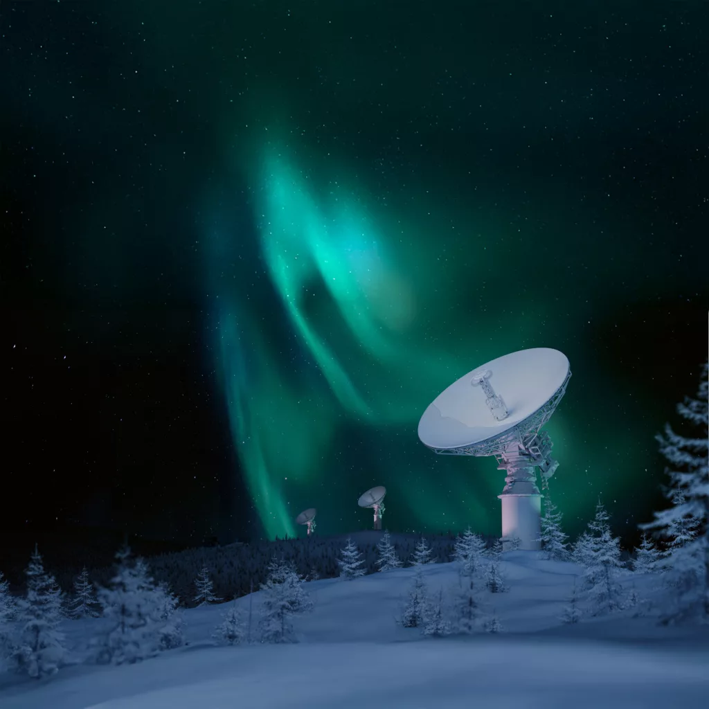 Antennas in snowy forest with aurora in the background