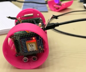 The students build their CanSats completely by themselves. A pink can satellite with electronics inside with a red blinking LED