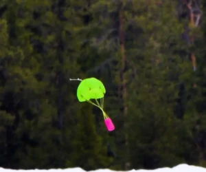 The CanSat safely lands using a parachute. A pink can satellite falling controlled with the help of a green parachute